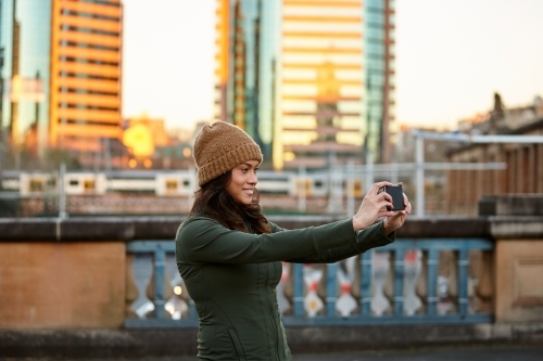 Young Asian woman having fun with mobile phone in city - Australian Stock Image