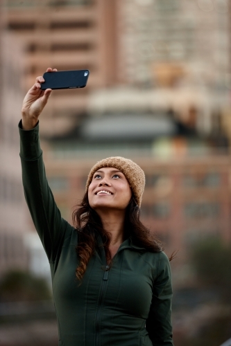Young Asian woman taking a selfie with mobile phone in city - Australian Stock Image