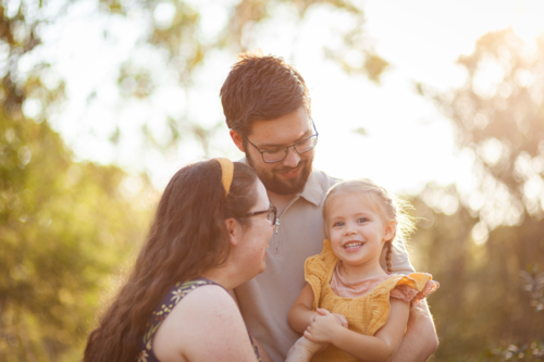Young Australian family of three together in golden light of bushland - Australian Stock Image