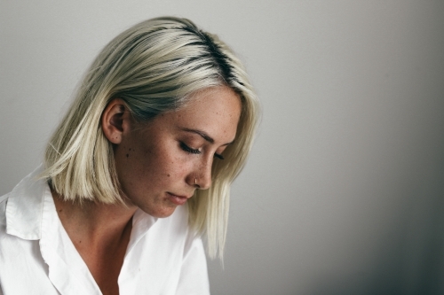 Young blonde woman looking down against a white background - Australian Stock Image