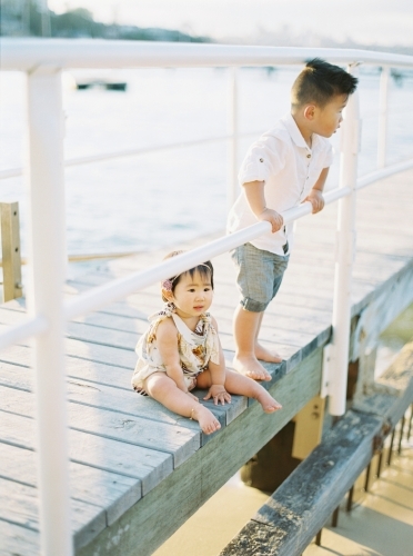 Young boy and baby sister on a wharf at the beach - Australian Stock Image