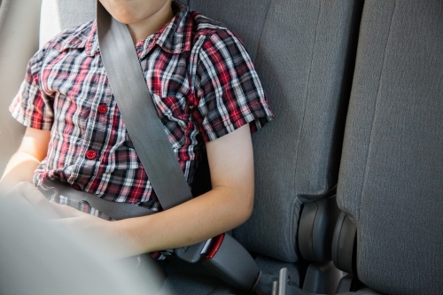 Young boy clicked in to car seat with grey seat belt - Australian Stock Image