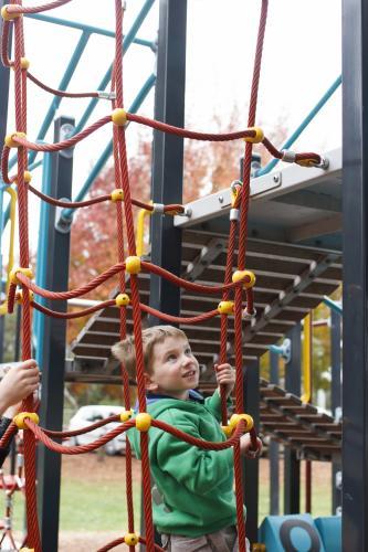 Young boy climbing on play equipment at the park - Australian Stock Image