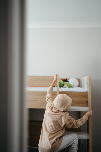 Young boy climbing up the ladder of the bunk bed. - Australian Stock Image