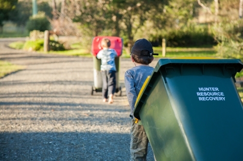 Young boy doing job taking bin across the road - Australian Stock Image