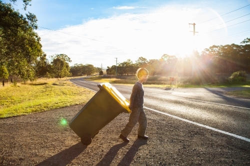 Young boy doing job taking bin across the road - Australian Stock Image