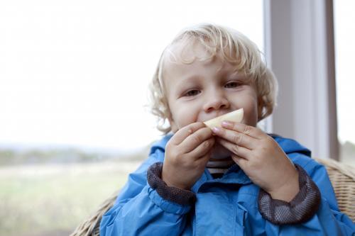 Young boy eating apple and making a funny face - Australian Stock Image