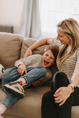 Young boy giggling while snuggling into mums side. - Australian Stock Image