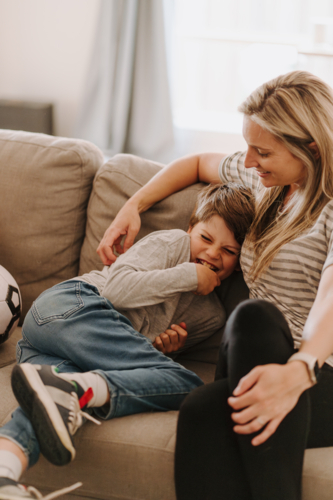 Young boy giggling while snuggling into mums side. - Australian Stock Image