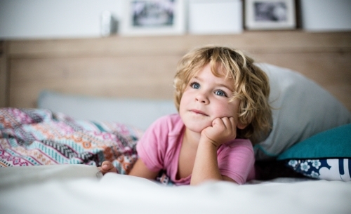 Young boy in bed in natural morning light - Australian Stock Image