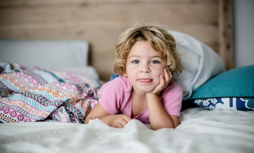 Young boy in bed in natural morning light - Australian Stock Image