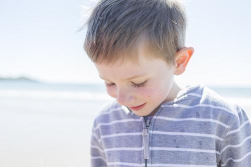 Young boy looking down at the beach - Australian Stock Image