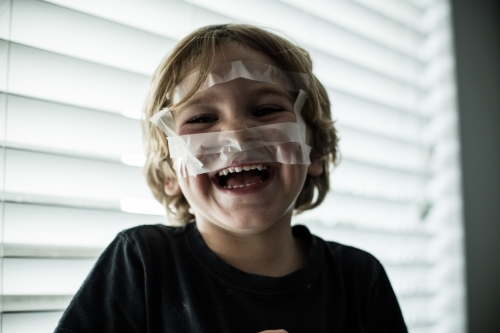 Young boy playing with sticky tape - Australian Stock Image