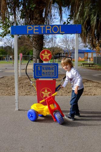 Young boy playing with toy bike pretending to fill with petrol - Australian Stock Image