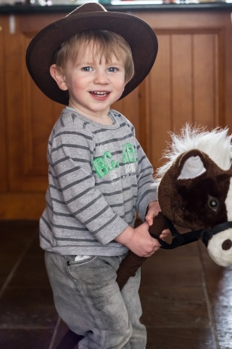 Young boy riding toy horse and smiling for camera