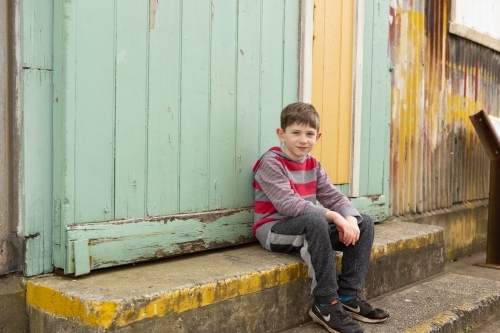 Young boy sitting on step - Australian Stock Image