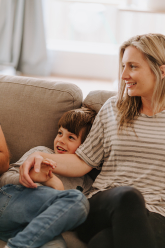 Young boy snuggles with mum on the couch. - Australian Stock Image