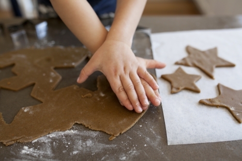 Young boy using cookie cutter to make gingerbread cookies