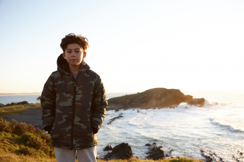 Young boy wearing camo jacket on sunrise - Australian Stock Image