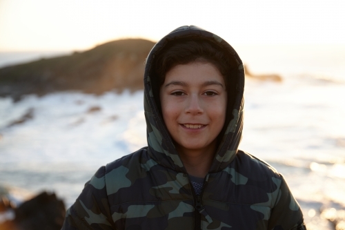 Young boy wearing camo jacket on sunrise - Australian Stock Image