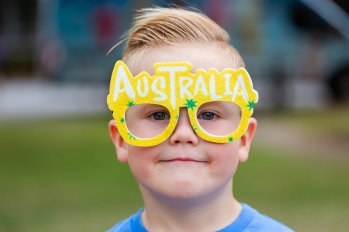 Young boy with glasses reading Australia on face at Australia Day eve event - Australian Stock Image