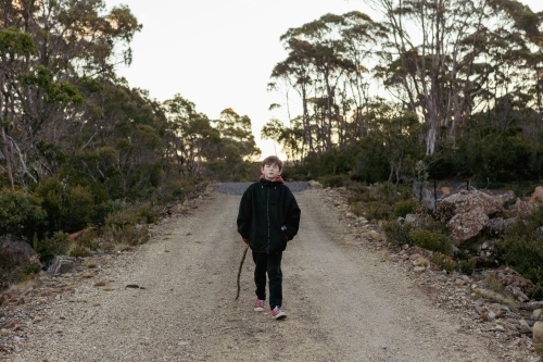 Young boy with stick on walking path - Australian Stock Image