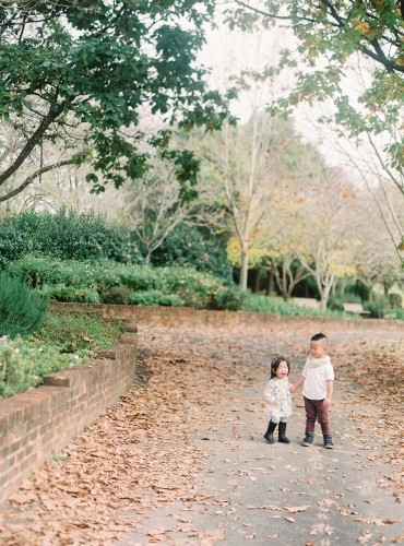 Young brother and sister holding hands in gorgeous park - Australian Stock Image