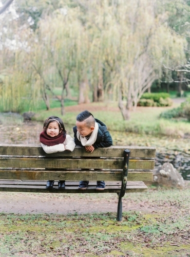 Young brother and sister standing on wooden bench in gorgeous outdoor surrounds - Australian Stock Image