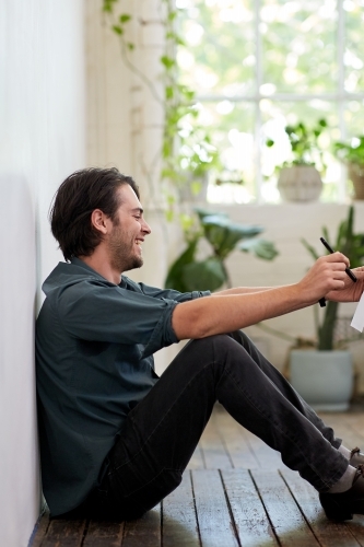 Young business man relaxing sitting on a timber floor in studio - Australian Stock Image