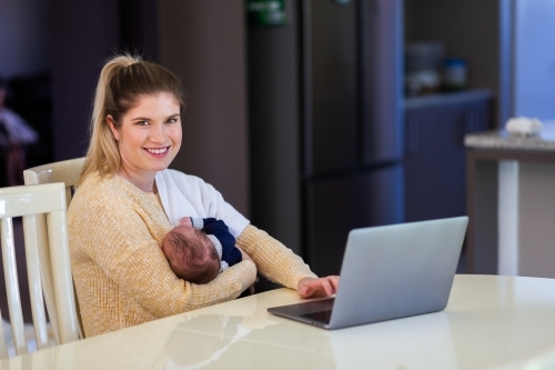 Young businesswoman mum working from home on laptop with newborn baby - Australian Stock Image