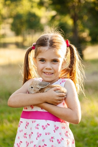 Young child cuddling her pet bunny rabbit - Australian Stock Image