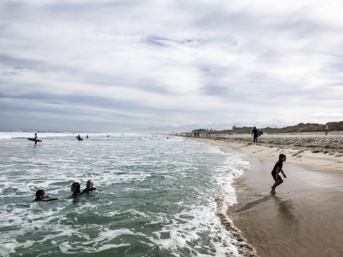 young children playing on the waters edge of the beach - Australian Stock Image