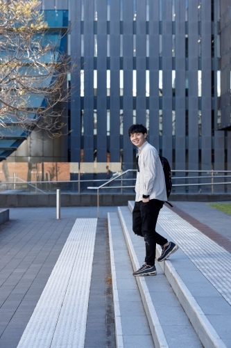 Young Chinese student walking on stairs at university campus - Australian Stock Image