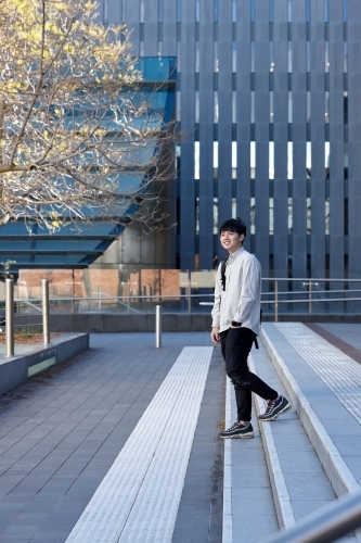 Young Chinese student walking on stairs at university campus - Australian Stock Image