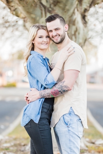 Young couple arm in arm standing with faces close together - Australian Stock Image