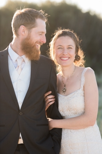 Young couple in portrait pose walk along together smiling. - Australian Stock Image