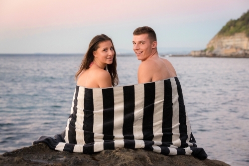 Young couple on the ocean rocks at sunrise - Australian Stock Image