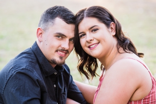 Young couple sitting close together smiling touching heads - Australian Stock Image