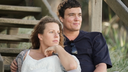 Young couple sitting on beach steps looking at ocean - Australian Stock Image