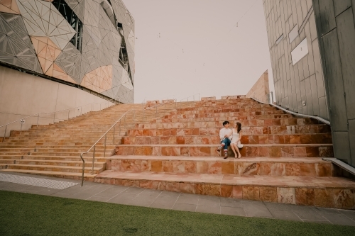 Young couple sitting together on steps at Federation Square - Australian Stock Image