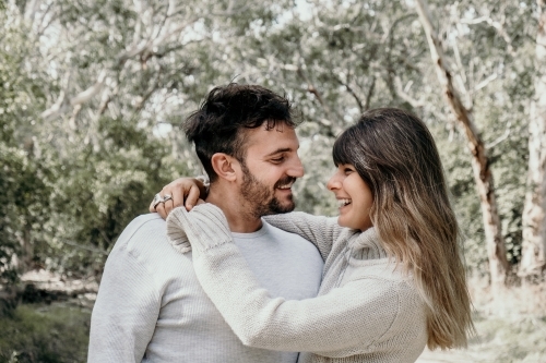 Young couple smiling at each other outdoors. - Australian Stock Image