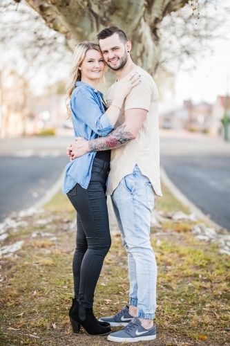 Young couple standing in each others arms smiling - Australian Stock Image