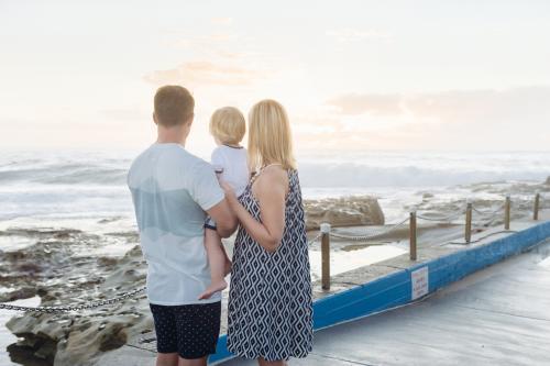 Young family watching the sunrise at the beach - Australian Stock Image