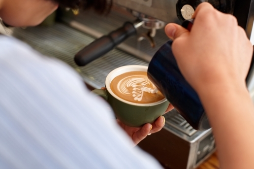 Young female barista preparing coffee with coffee machine - Australian Stock Image