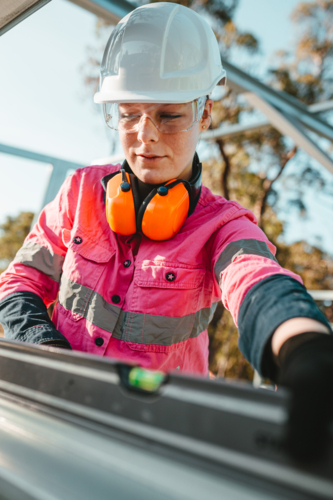 Young female construction worker using her level tool. - Australian Stock Image