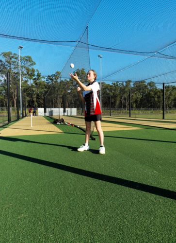 Young female cricketer practicing in the nets with a cricket ball - Australian Stock Image