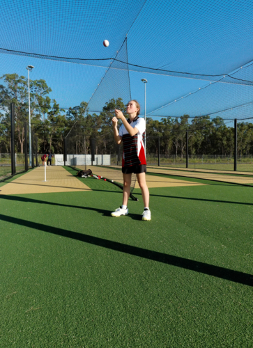 Young female cricketer practicing in the nets with cricket ball - Australian Stock Image
