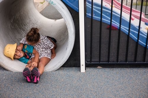 Young First Nations girl and boy playing together in a tunnel - Australian Stock Image