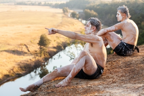 Young First Nations man storytelling while on edge of cliff on country - Australian Stock Image