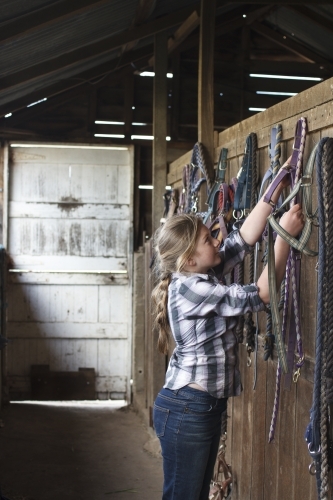 Young girl at horse riding farm in tack shed - Australian Stock Image